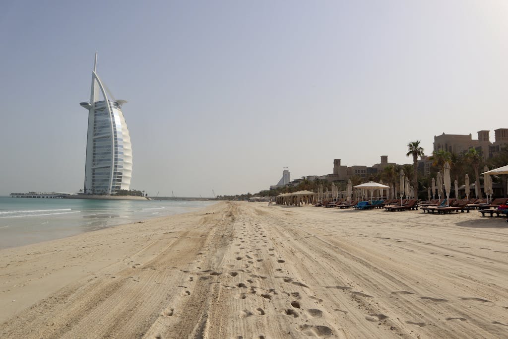 A stunning view of Burj Al Arab against the clear sky on a serene beach in Dubai, UAE.