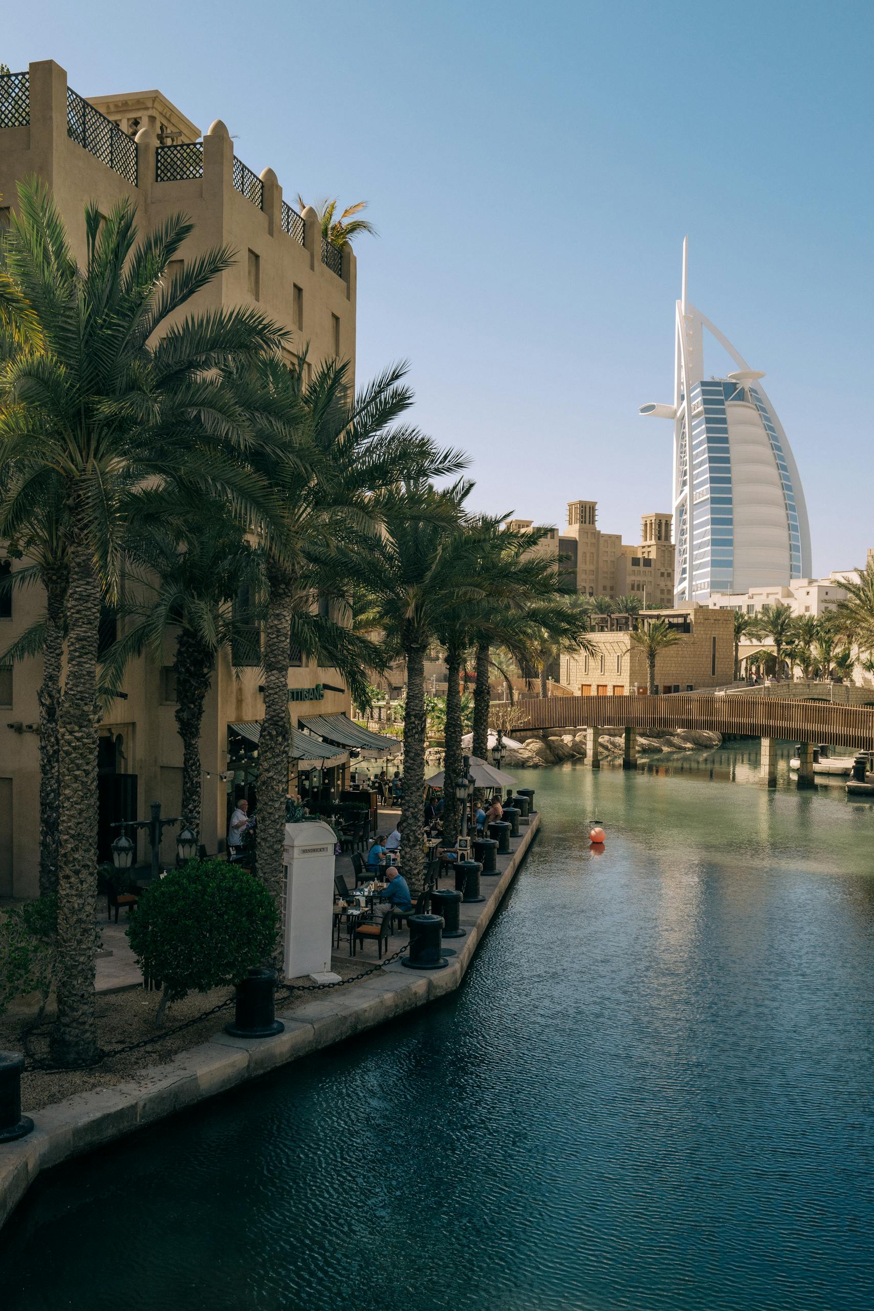 Beautiful view of Burj Al Arab with a canal and palm trees in Dubai, UAE.